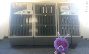 Venonat, a buglike pokemon, sits at the laptop kiosk in the library