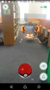 Crabby, a crablike pokemon creature, sits in the library by books.