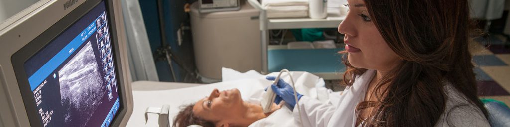 Picture of a Sonography student performing an ultrasound on a patient in the Sonography lab