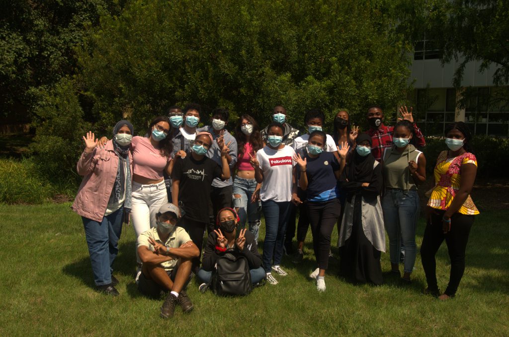 Alexandria Campus Community College Initiative students wearing masks smile and wave.