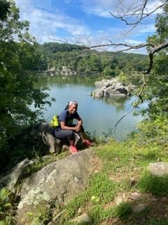 Backpacker takes a rest from backpacking in nature with beautiful lake and mountain in background.