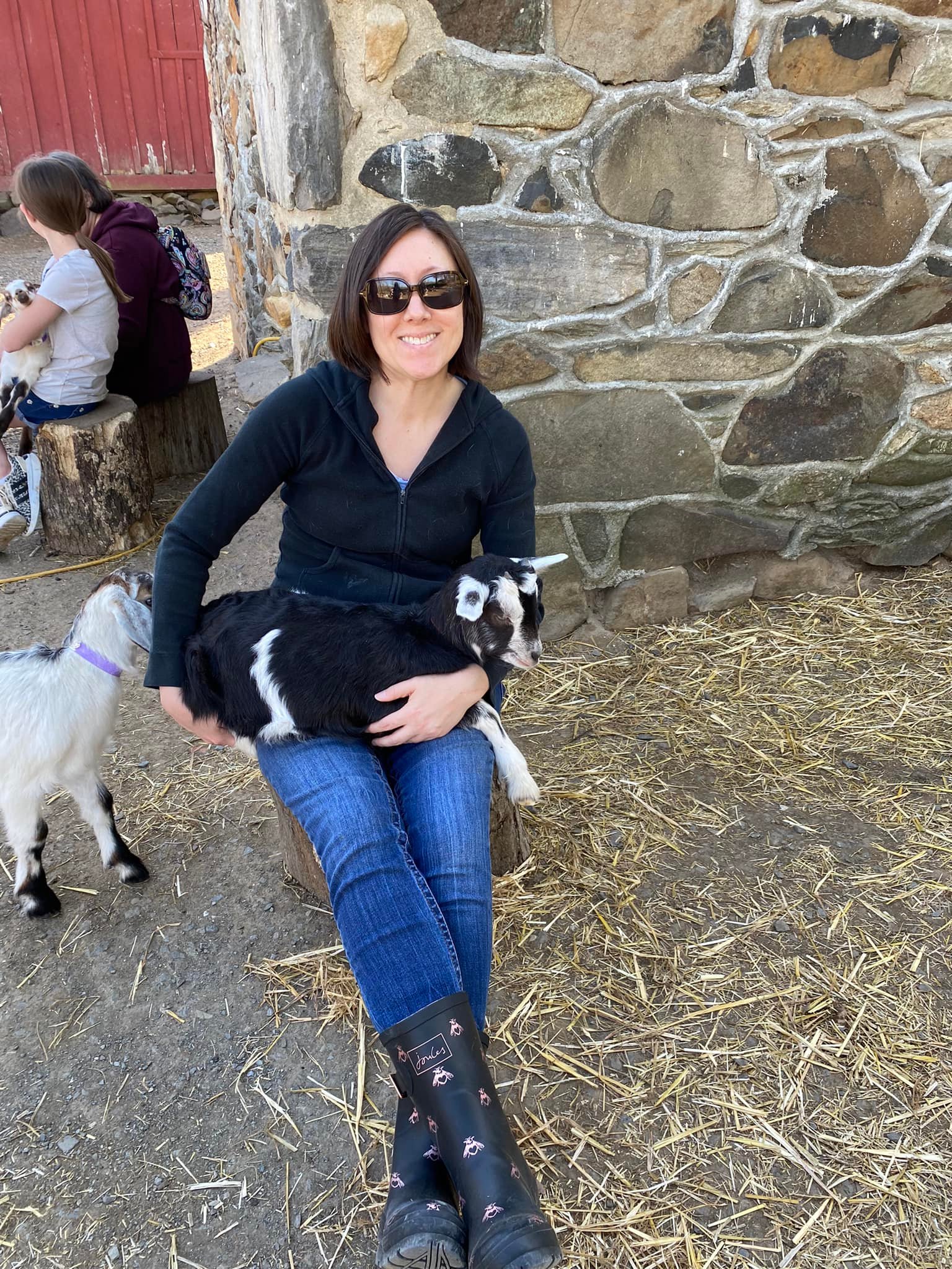 Lisa Scott sits holding a tiny black and white goat.