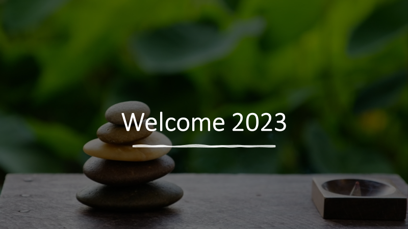 Photo: Rocks stacked against a backdrop of green forest. Welcome 2023 inscribed in white.