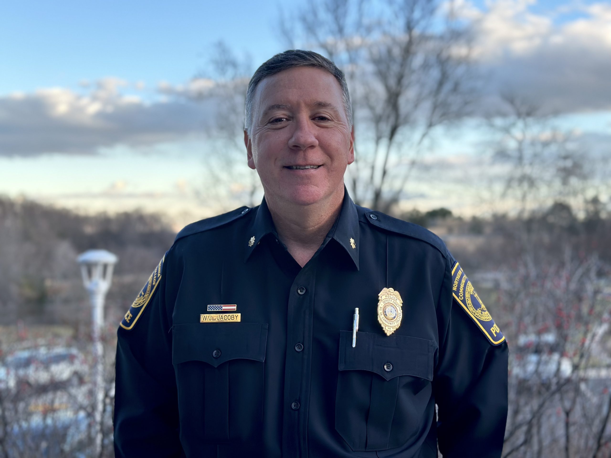 NOVA's New Police Chief Jake Jacoby poses beside the Brault Building with a beautiful winter sky behind him.