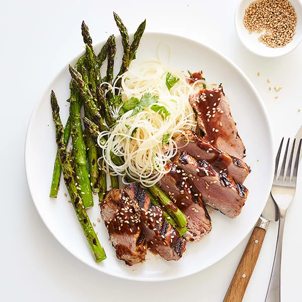 White plate with hoisin-glazed tuna, rice noodles and asparagus