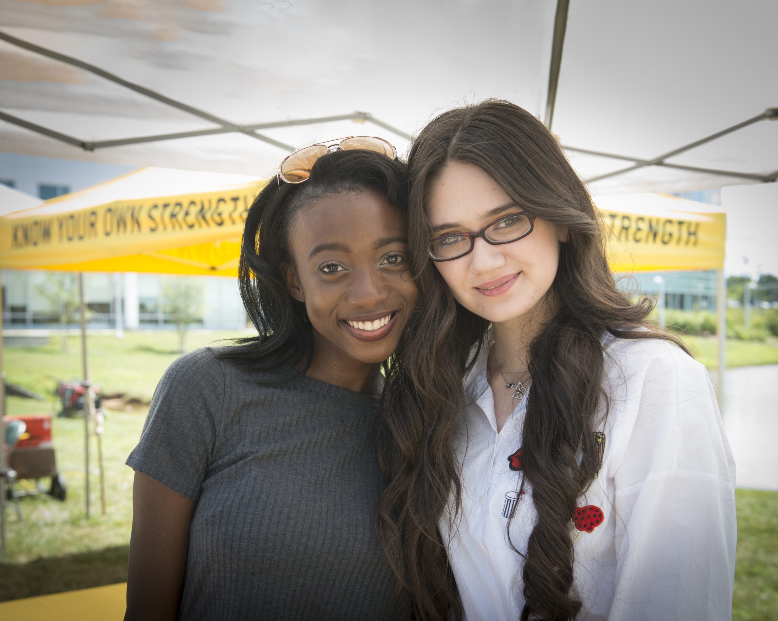 Two students smile together at a Giving Day Pop-up event.