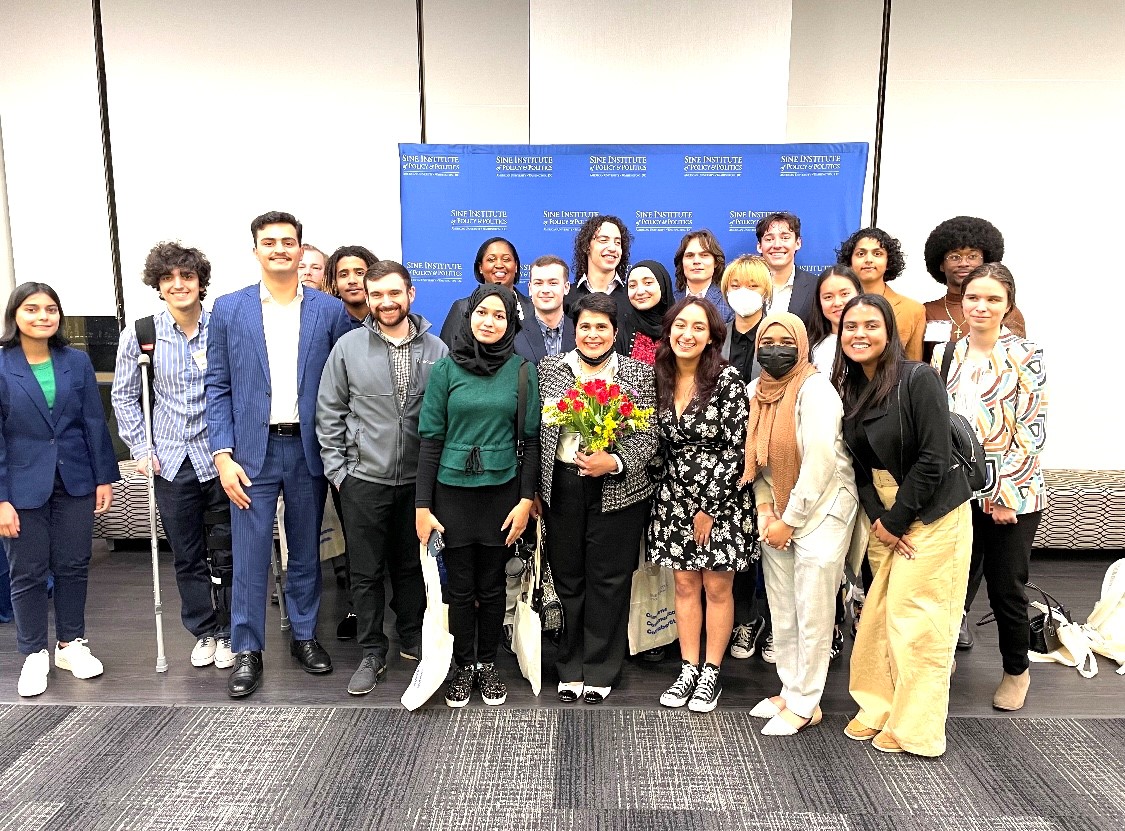 Energized students gather around Dr. Gulshan (holding a bouquet of yellow daffodils and red tulips).