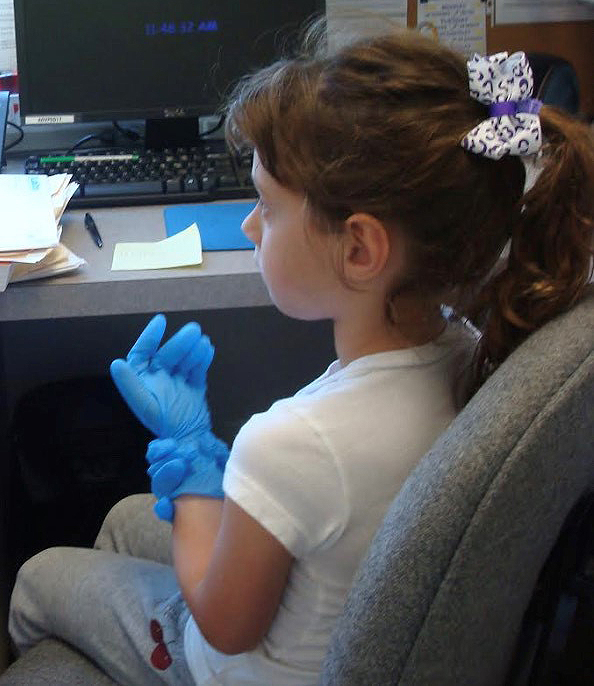 Young Sydney at about 8 years old sits in an office chair and puts on latex medical gloves while "working" at her grandfather's medical practice. The start of things to come!