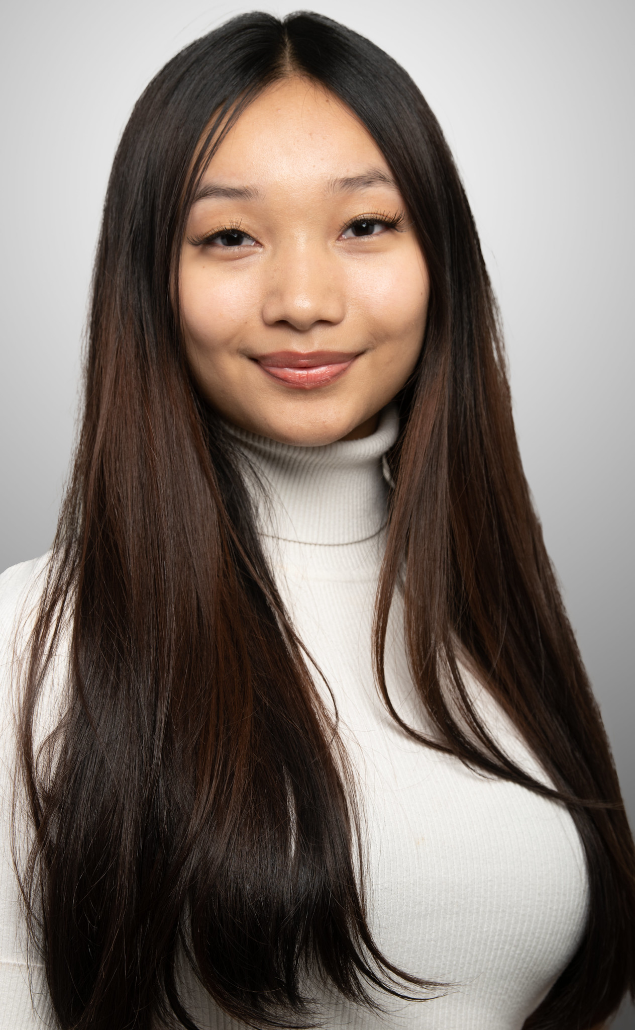 Grace Rai from Nepal poses for her high school senior photo with waist length black hair and a white turtle neck shirt