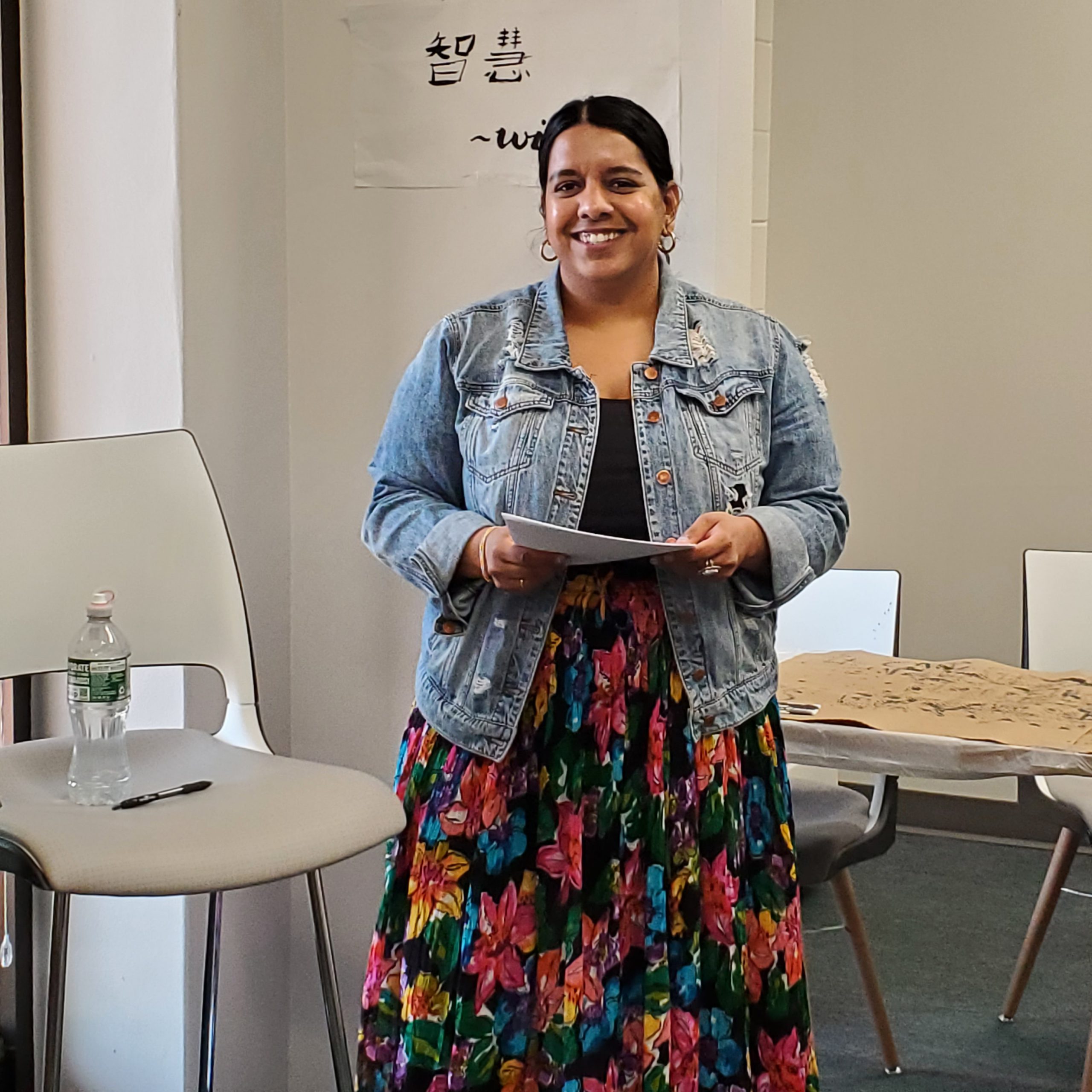Sandhya Oaks, wearing a brightly-colored floral broom skirt and a denim jacket prepares to present to those gathered at the AAPI Intercultural Learning Center