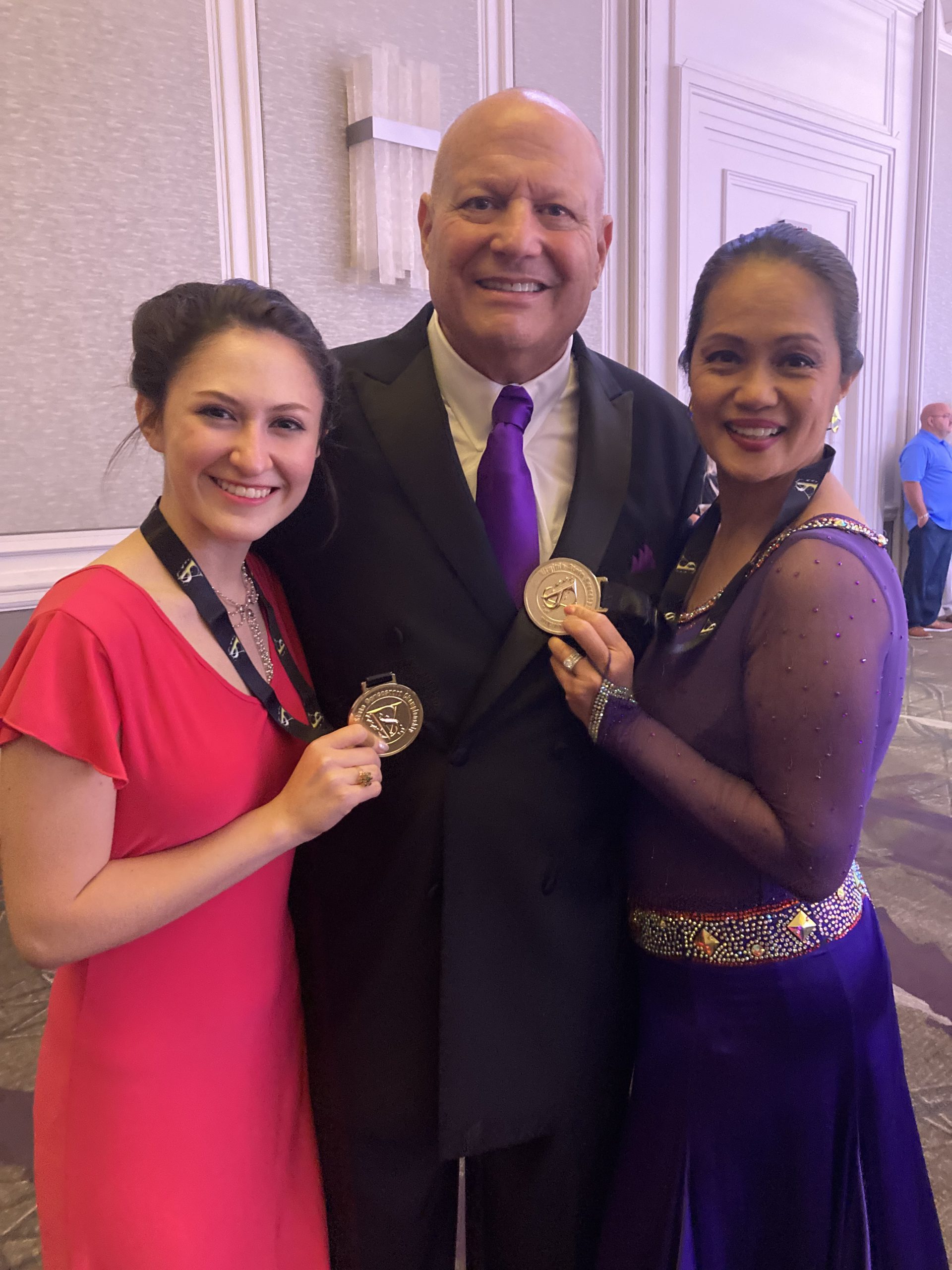 Alan Golombek (center), his student, Elizabeth Weinand (left) and his wife Thuy, pose outside the ballroom with their medals.