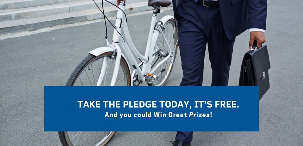 Car Free Day Image. Photo of the lower half of a man carrying a brief case and walking a white bicycle on the sidewalk in front of stone stairs. Blue banner with white type: Take the Pledge Today, It's Free. And you could win great prizes!