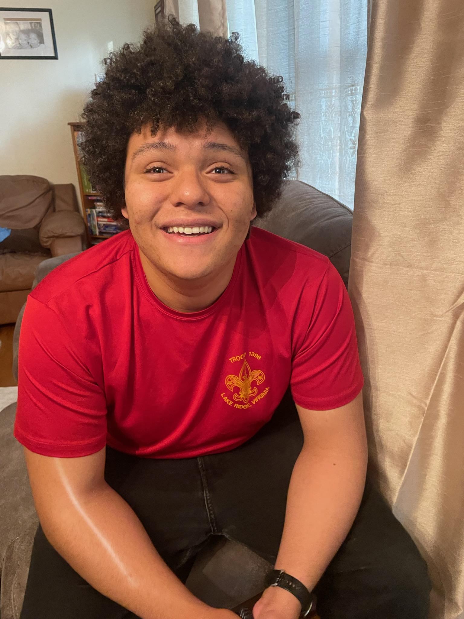 Jaden Todd wearing a bright red tee shirt and black jeans smiles for the camera.