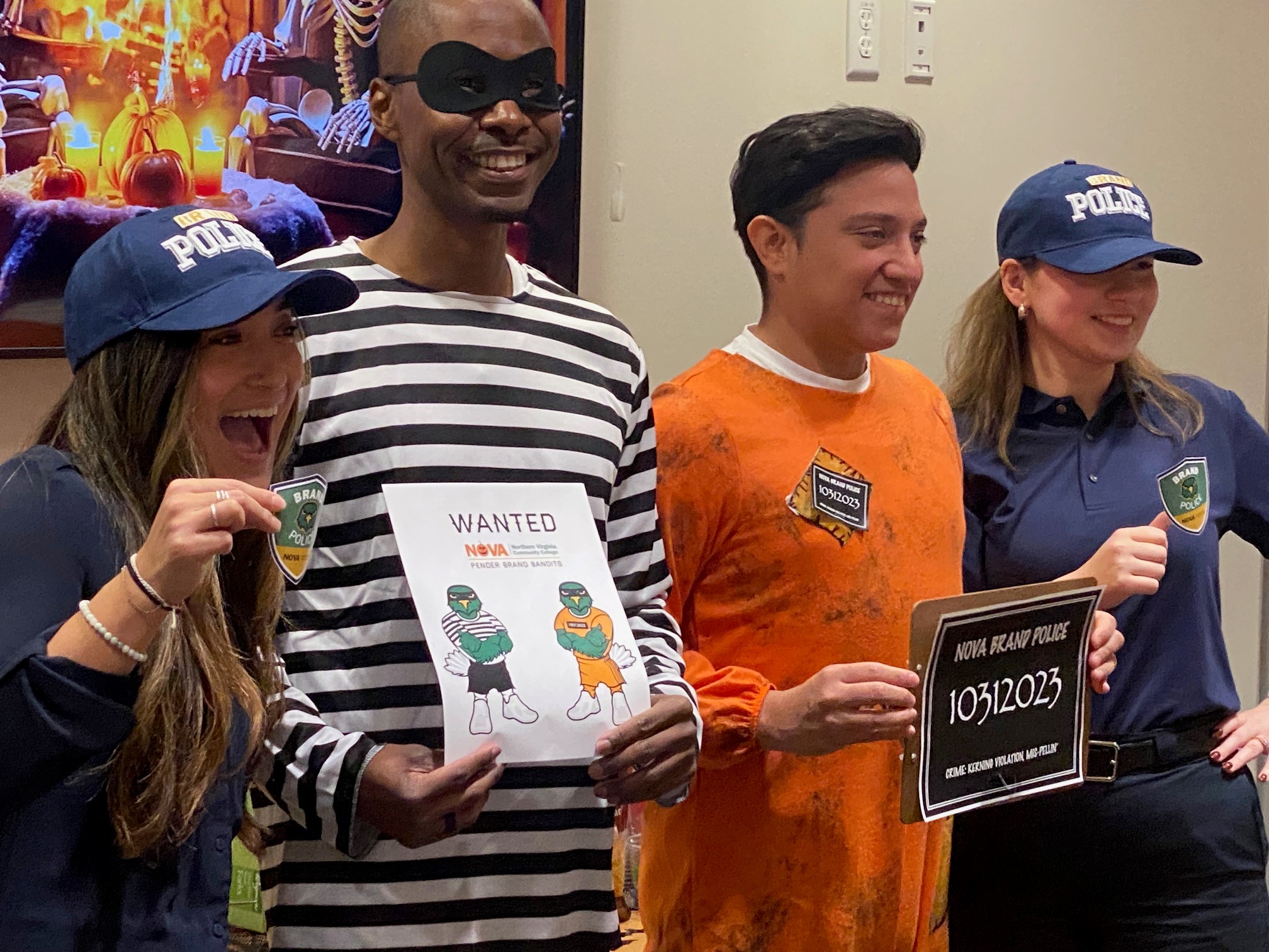 NOVA Brand Police, Julia Killough (far left) and Abby Parsons (far right) hold up their brand police badges. Both are wearing navy blue shirts and dark pants and navy blue hats emblazoned with "Brand Police." Julia and Abby have captured two NOVA Brand Bandits (or Brandits) John Whitten (center left) wearing a long sleeved black and white striped tee and holding a paper with "Wanted," a NOVA logo using a pumpkin for the O in NOVA (a no-no, in case you didn't know) and the words Pender Brand Bandits, with two ACE nighthawks, arms crossed across their chests, wearing a bandit mask and dressed as John and Otto are (one in black and white striped tee and black shorts and the other in an orange jumpsuit) Otto Najera (center right) wearing a prisoner's orange jumpsuit and holding a mugshot board marked "NOVA Fraud Police 10312023, Crime: Kerning Violation, Mis-pellin'. Adhering to the NOVA brand standards is serious business, y'all.