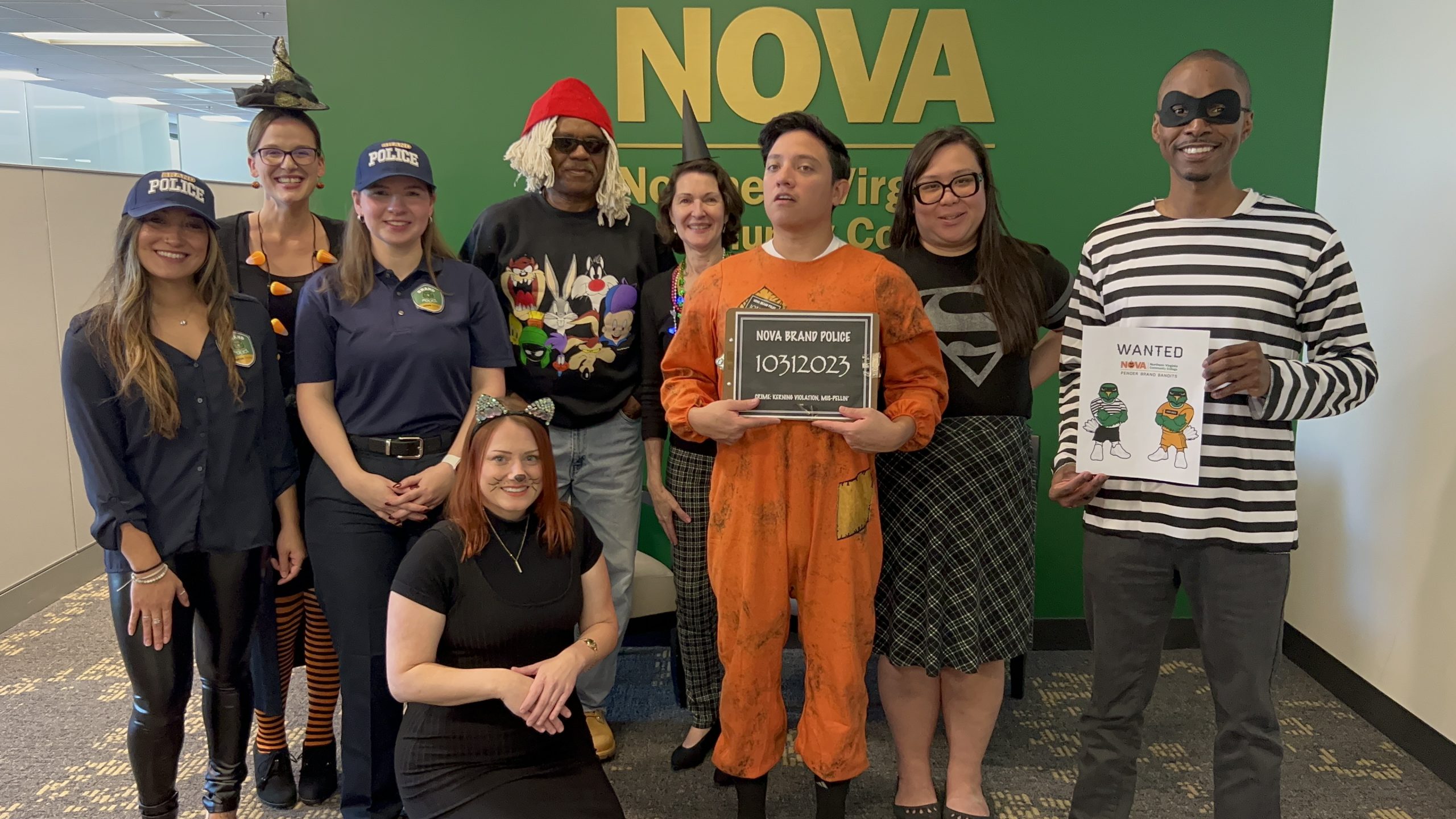 Back row, from left: Lucy Williams wearing a witch hat and a light-up candy corn necklace; Terry Wilson, dressed as all the things he found in his hall closet--a mop wig, red cap, booths and a swiffer; Teresa Sweeney, wearing a witch hat and light-up ghost necklace; Hoang Nguyen, wearing a black and grey plaid skirt and a black tee with a silver Super Girl emblem; Center row, from left: Julia Killough and Abby Parsons, wearing their NOVA brand police gear; Otto Najera in an orange jumpsuit holding his mugshot board and John Whitten in a black and white striped long-sleeved tee and black pants holding his Wanted poster; Kneeling in front, Angela Manning, dressed as a cat.