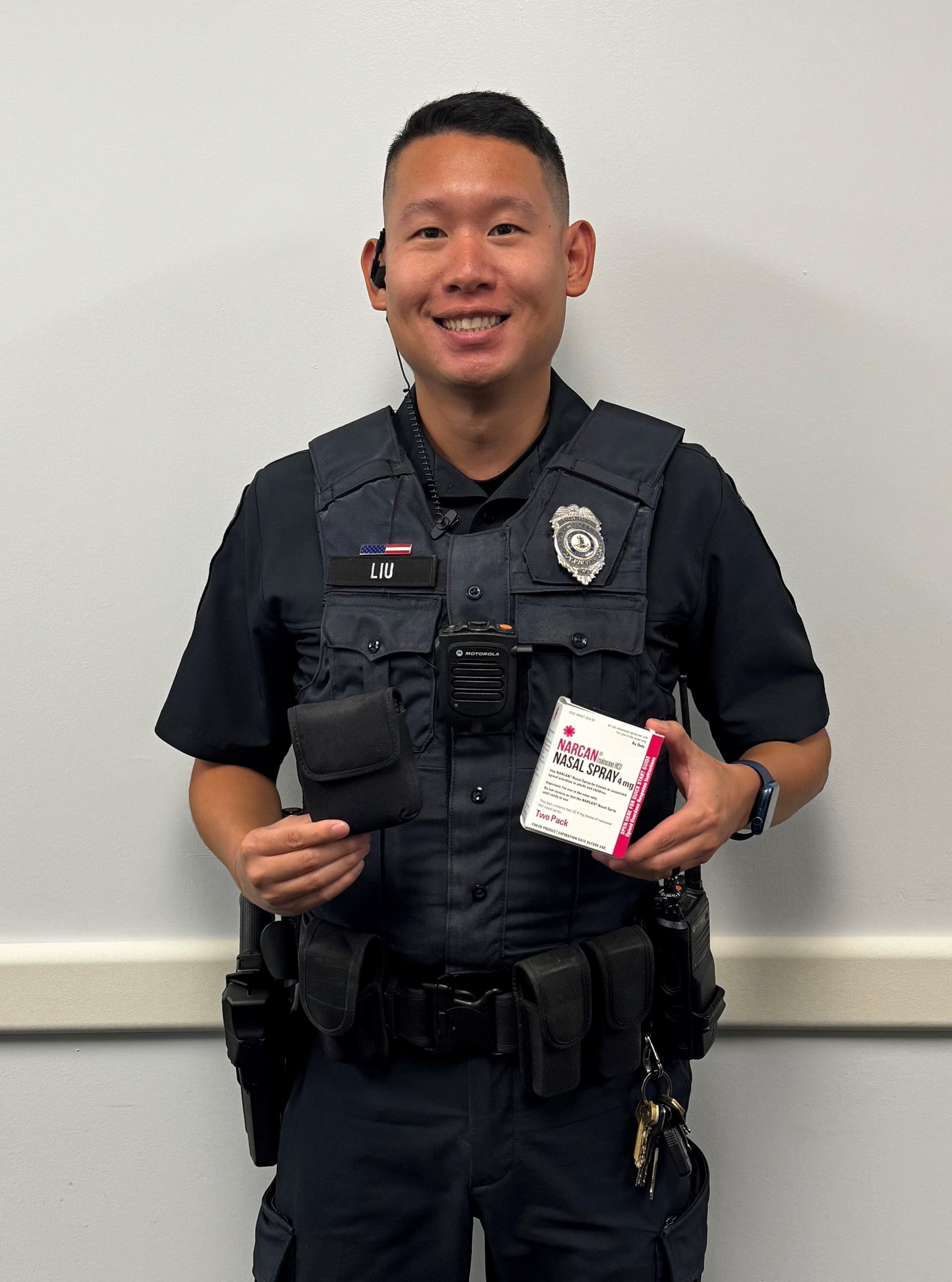 Officer Jeffrey Liu holds a pink and white box of Naloxone, also known as Narcan.