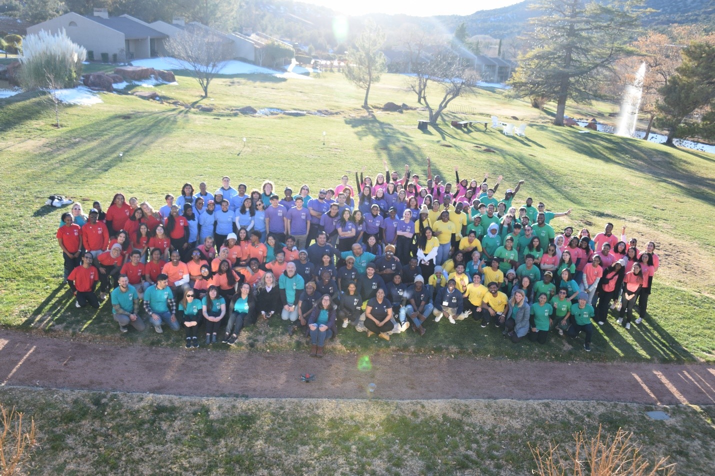 A group photo taken in the grass at the conference location. Members from each school represented wear the same color shirt. CCI Program hosts and participants from  the College of DuPage in Illinois, Fox Valley Technical College in Wisconsin, Kirkwood Community College in Iowa, Mesa Community College in Arizona, Northampton Community College in Pennsylvania, Northern Virginia Community College’s Alexandria and Annandale Campuses in Virginia, Sinclair Community College in Ohio, and Valencia College in Florida.