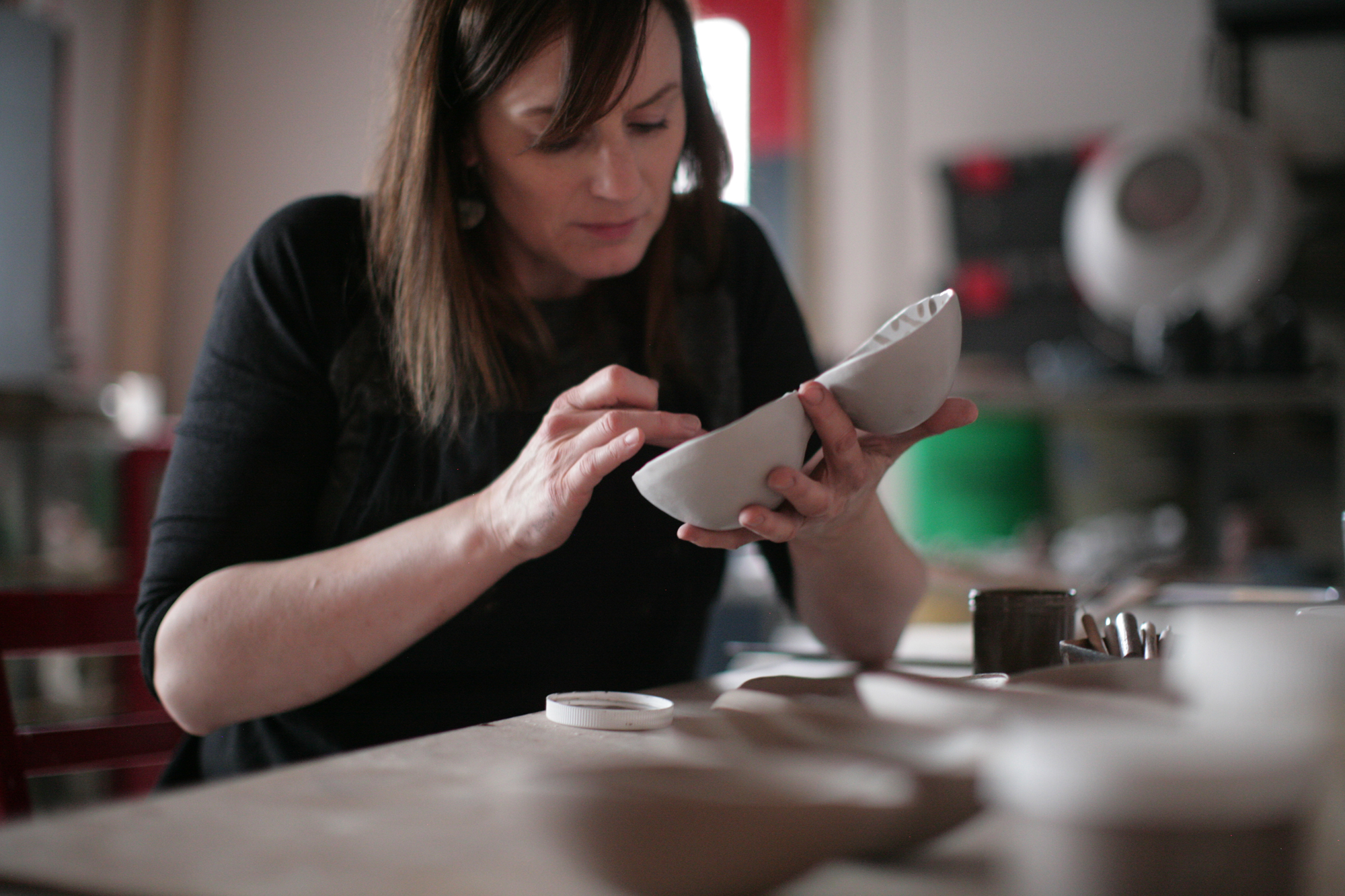 Artist Rhonda Willers in her studio, putting the finishing touches on a piece of pottery. 