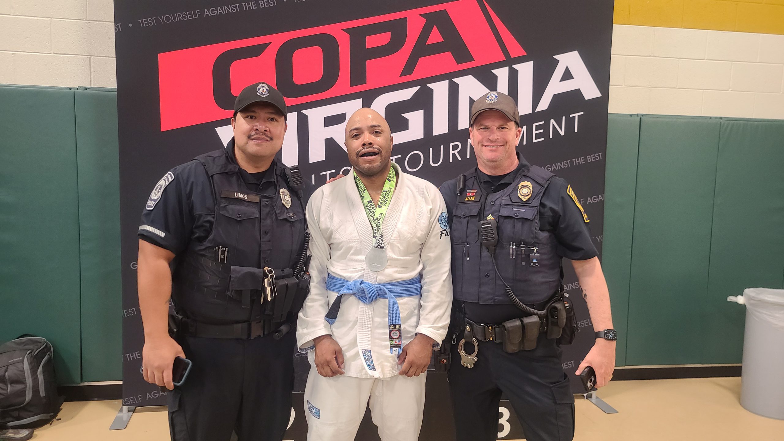 Three men stand in front of a black, red and white Copa Virginia Jiu-Jitsu Tournament backdrop. Left to Right: Officer Tyrone Limos, NOVA Police, Annadale Campus; Officer Jarrin Moore and Sgt. Stephen Allen, NOVA Police, Annandale Campus