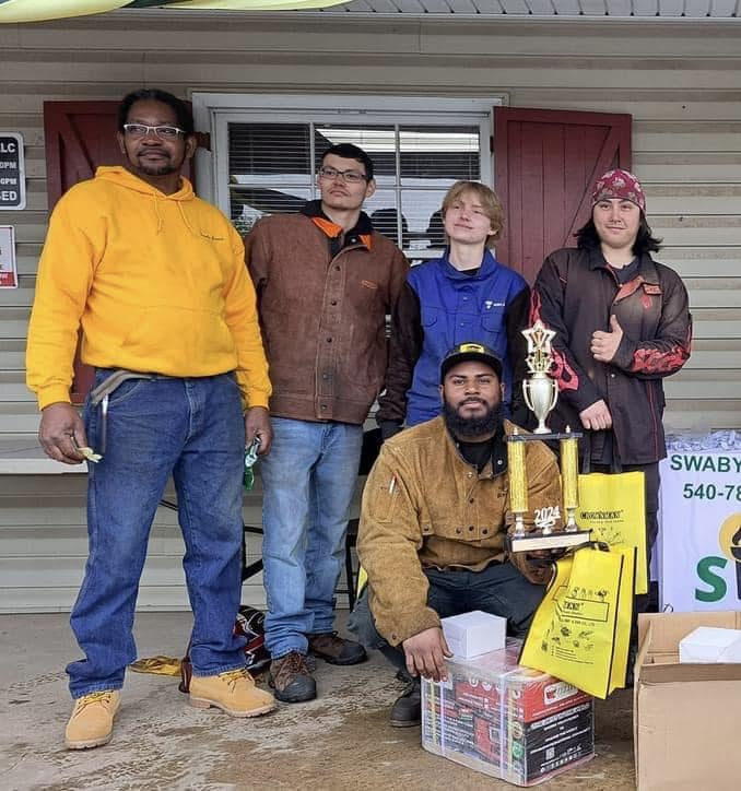 Photograph of, from left to right: Owner of the Swaby Group, LLC, Lee Swaby with welding students Elliot Scott, Caroline Patterson, Matthew Wolfe and Marlin Adams.