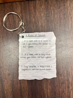 Photo of keychain with Jason Armstrong's creation: a piece of lined notebook paper with the 3 Rules of Spanish in a font that looks like handwriting on it.