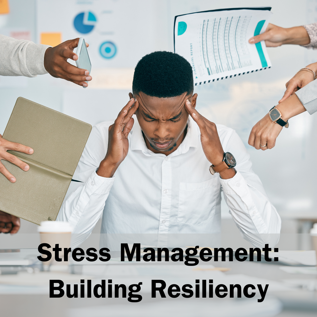 Stock photo of man sitting at his desk with hands at his temples. Around him are everyday workplace stressors, including multiple people reaching out with various items, including a notebook, phone, report and wristwatch. At the bottom of the photo is the following black text: "Stress Management: Building Resiliency."