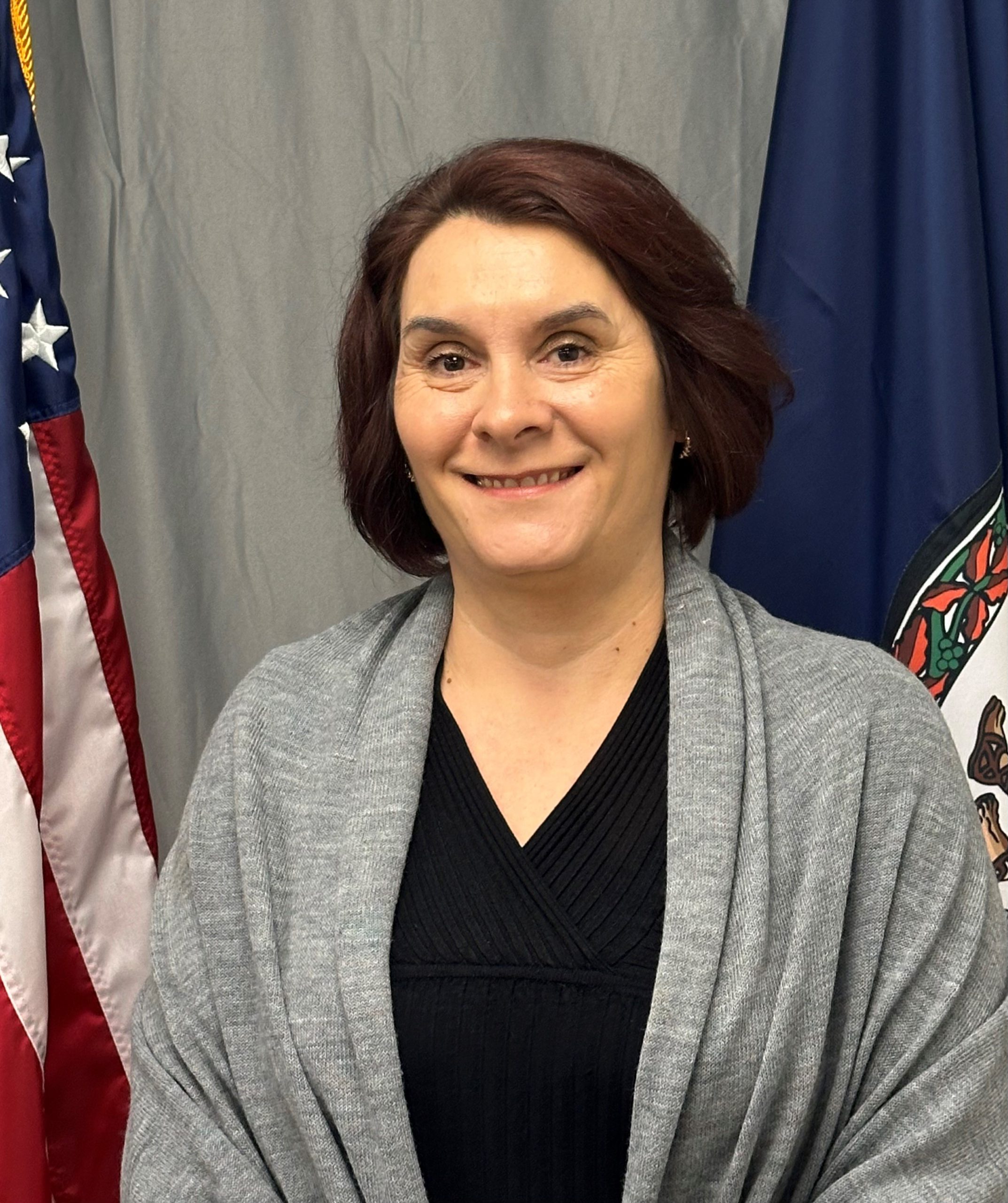Professional photo of Ionela Manown with grey curtain behind her, along with the American and Virginia flags.