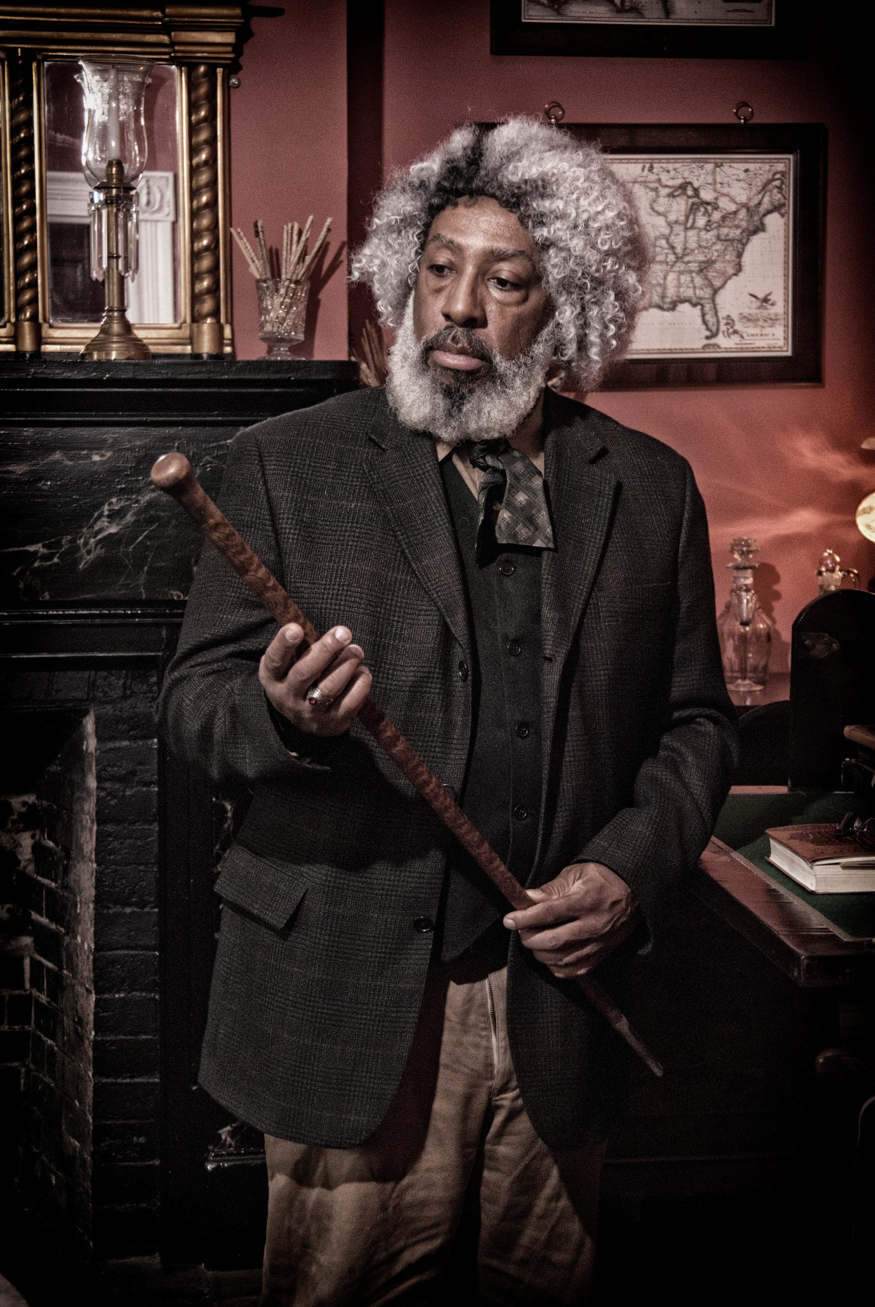 Nathan Richards, playing the part of Frederick Douglass, holds a wooden cane in his hands