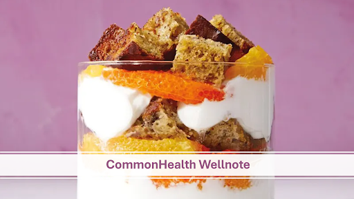 The image features a close-up of a glass filled with layers of yogurt, orange segments and cubed pieces of what appears to be whole grain or spiced cake. The dessert is set against a vibrant purple background. A text overlay in the center reads CommonHealth Wellnote" in purple font with a white and pink horizontal bar design. The presentation of the dish highlights a mix of textures and colors, creating an appealing, nutritious-looking treat.